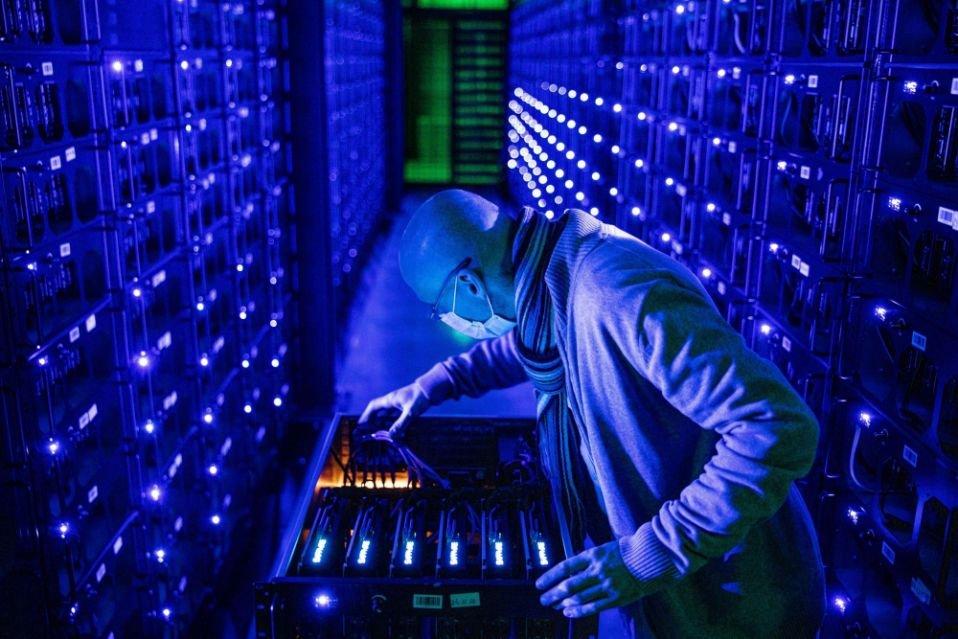 A close-up of a miner meticulously examining the internal components of a high-powered mining rig.